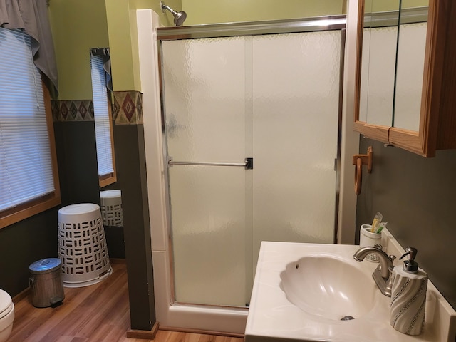 bathroom with a shower stall, toilet, vanity, and wood finished floors