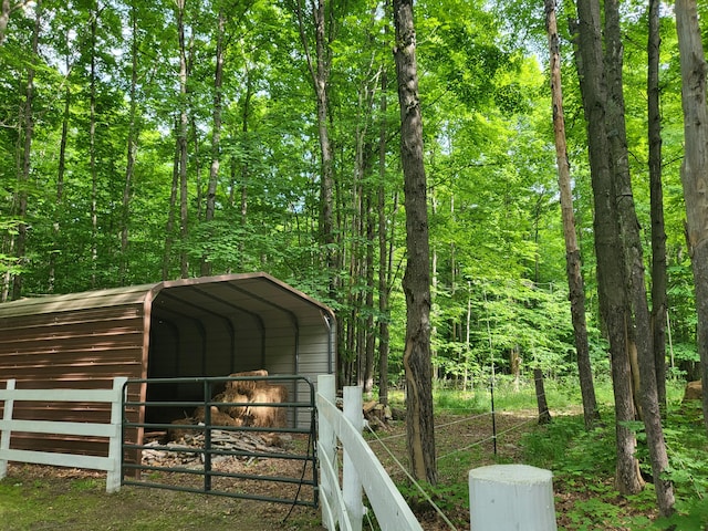 view of outbuilding with a detached carport and a forest view