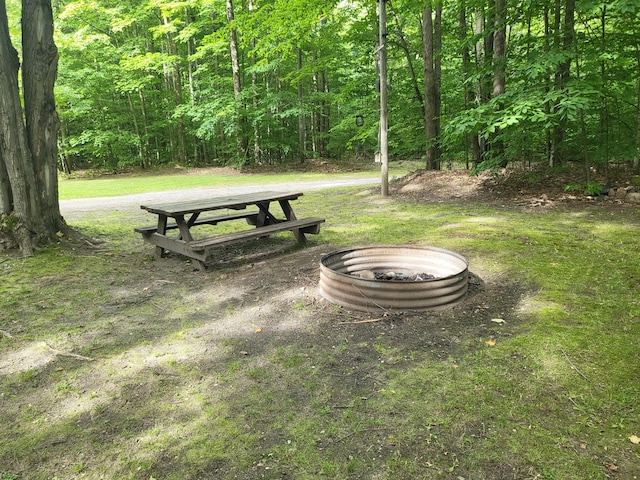 surrounding community featuring a yard, a fire pit, and a view of trees