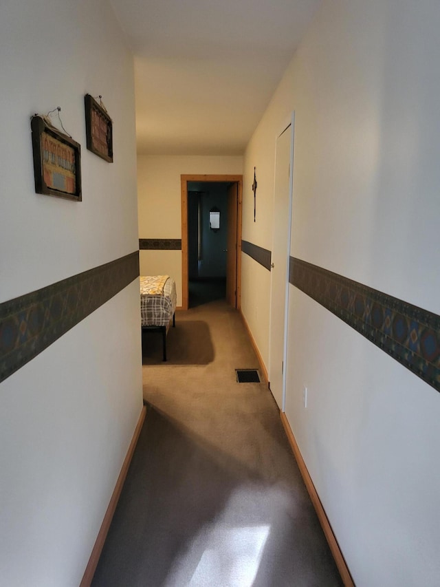 corridor with visible vents, baseboards, and carpet