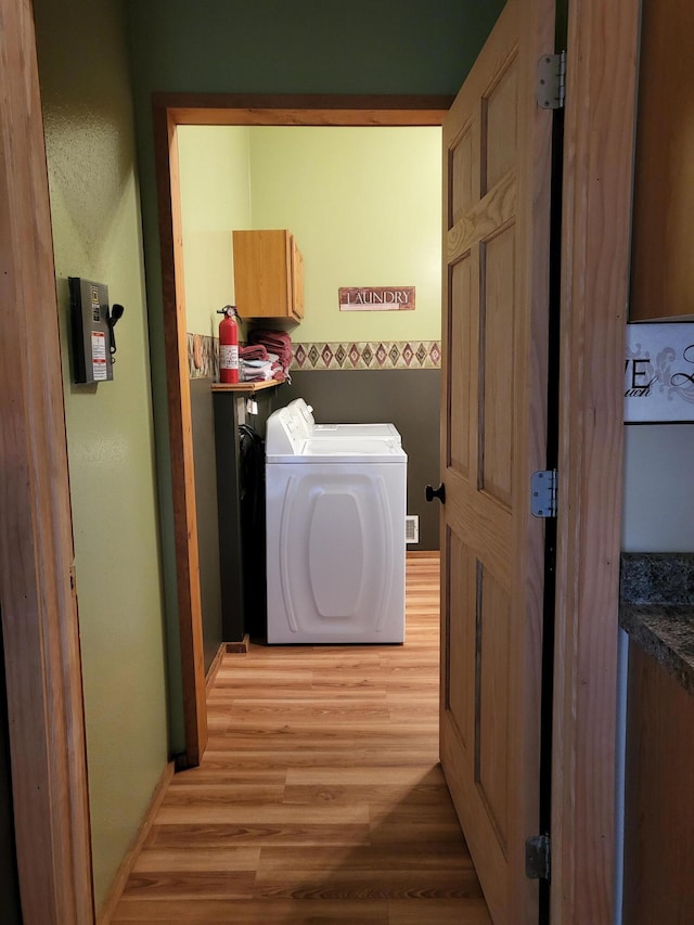 laundry area with cabinet space, separate washer and dryer, baseboards, and light wood finished floors