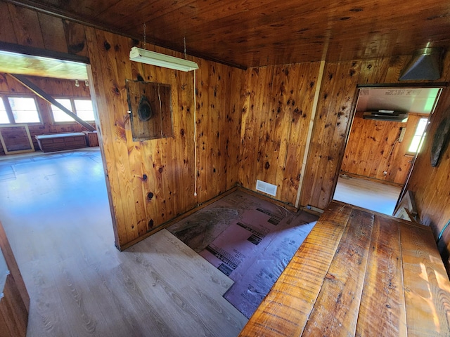 empty room with wooden ceiling, wooden walls, wood finished floors, and visible vents