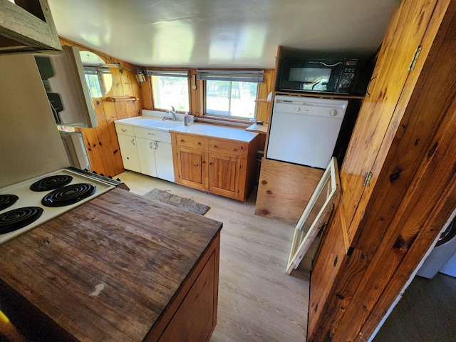 kitchen featuring a sink, light wood-type flooring, black microwave, and white dishwasher