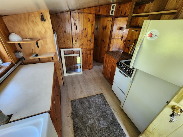 kitchen featuring wood walls, light wood-style flooring, brown cabinets, white appliances, and open shelves