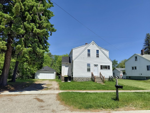 view of front of home featuring entry steps, a front lawn, a detached garage, and an outdoor structure