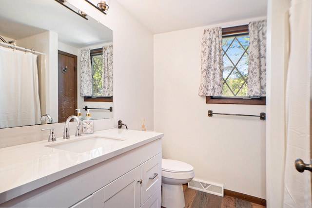 full bathroom with visible vents, baseboards, toilet, wood finished floors, and vanity