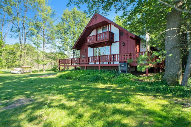back of property with cooling unit, a lawn, and a balcony