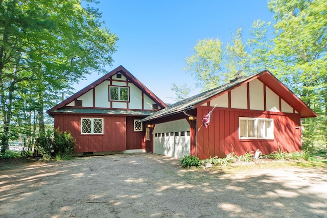 view of front of house featuring a garage, dirt driveway, and a shingled roof