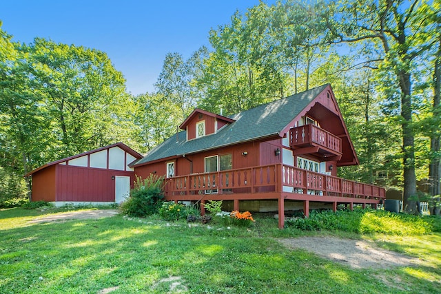 rear view of property with a balcony, a lawn, driveway, and a shingled roof