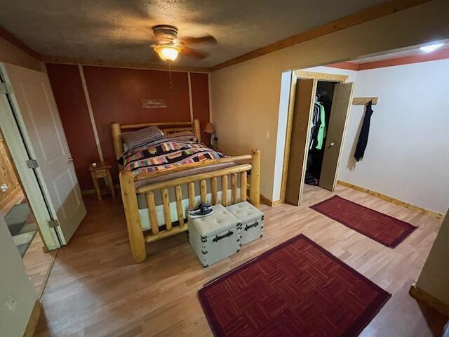 bedroom with a ceiling fan, wood finished floors, and ornamental molding