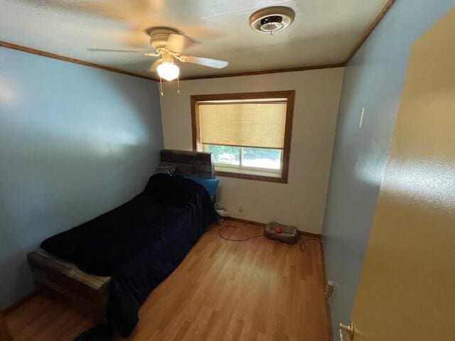 bedroom featuring a ceiling fan, crown molding, and wood finished floors