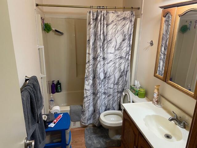 full bath featuring shower / bathtub combination with curtain, toilet, wood finished floors, and vanity