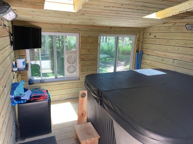 bedroom featuring wooden ceiling, a skylight, multiple windows, and wood walls