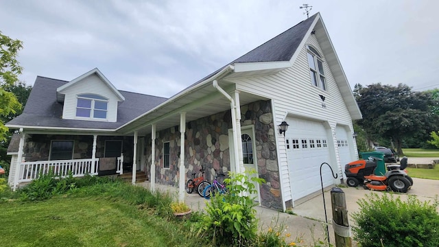 551 S US-23, Harrisville, MI 48740 - view of front of house featuring stone siding, covered porch, driveway, and a garage