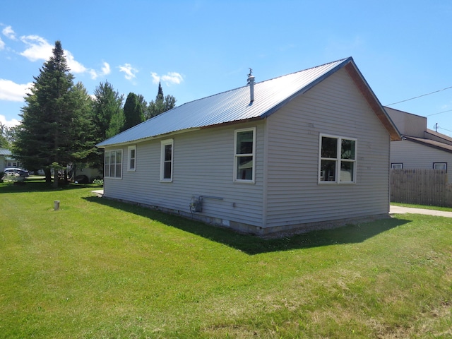 rear view of house with a yard, fence, and metal roof