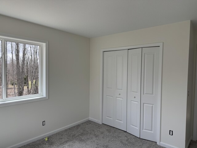 7805 Gray Hawk Ct, Gaylord, MI 49735 - unfurnished bedroom featuring baseboards, multiple windows, carpet, and a closet