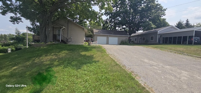 ranch-style home with an outbuilding, an attached garage, a front yard, and driveway