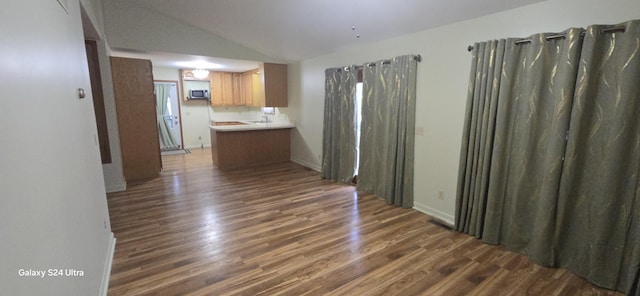 unfurnished dining area featuring vaulted ceiling, baseboards, and dark wood-type flooring