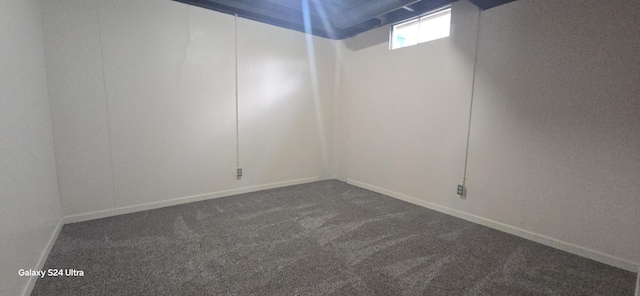 empty room with baseboards and dark colored carpet