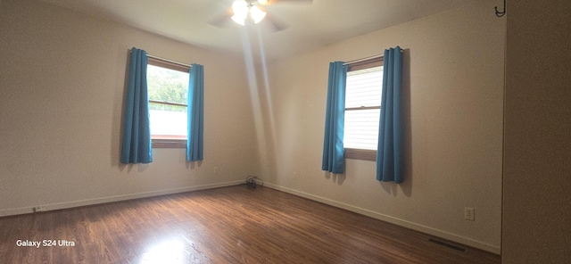 unfurnished room with a wealth of natural light, visible vents, baseboards, and wood finished floors