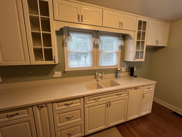 kitchen with a sink, dark wood finished floors, white cabinets, light countertops, and glass insert cabinets