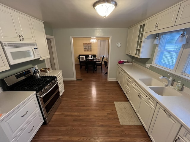 kitchen with white microwave, glass insert cabinets, double oven range, white cabinets, and a sink