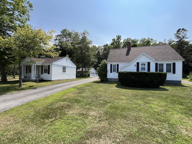 view of front of property with aphalt driveway, a chimney, a front lawn, and a shingled roof