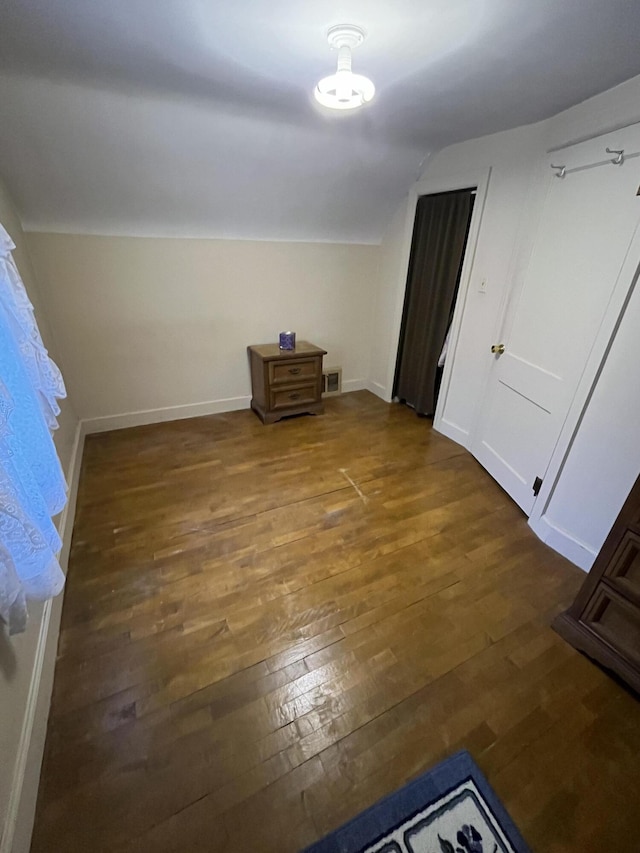 unfurnished bedroom with vaulted ceiling, baseboards, visible vents, and hardwood / wood-style flooring