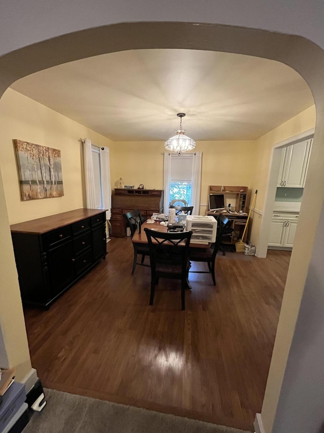 dining room featuring arched walkways, dark wood finished floors, and an inviting chandelier