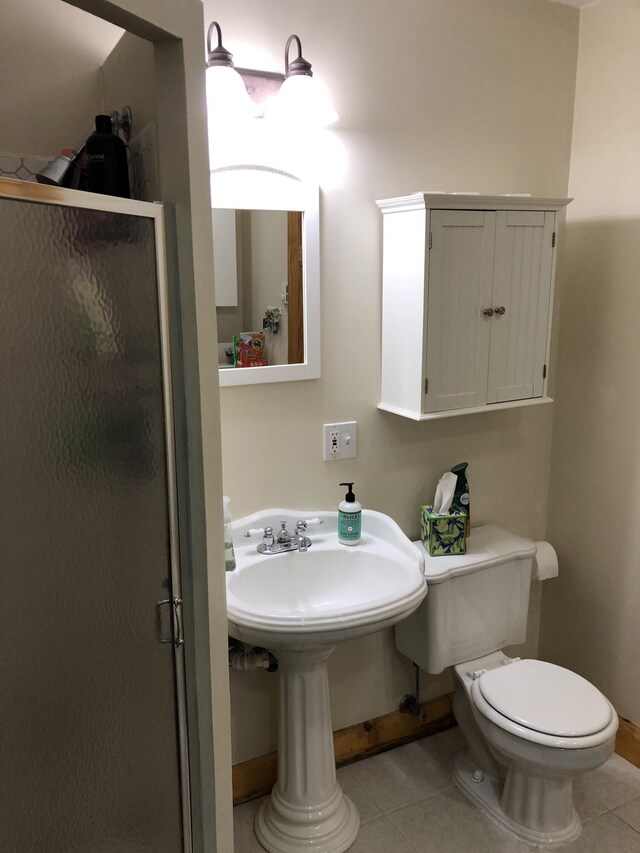 bathroom with tile patterned floors, toilet, baseboards, and a stall shower