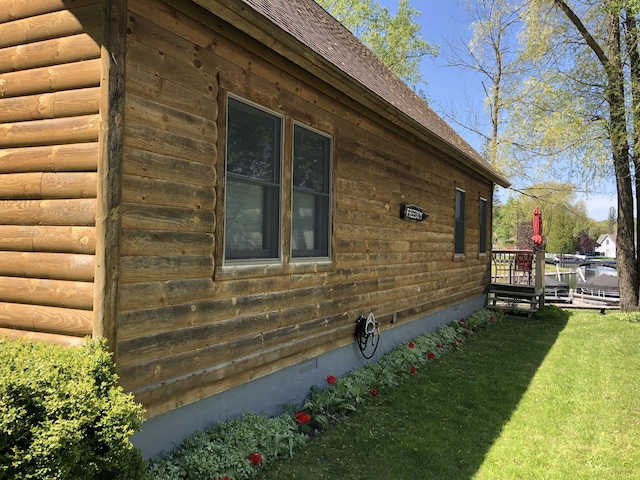 view of side of property with faux log siding and a yard