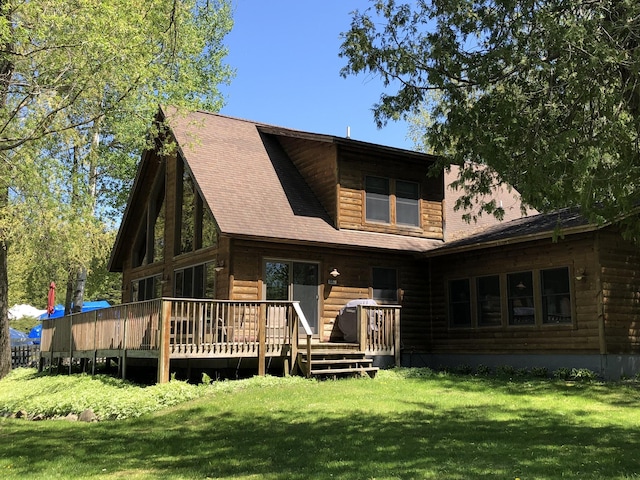 rear view of property with a lawn, roof with shingles, and a deck