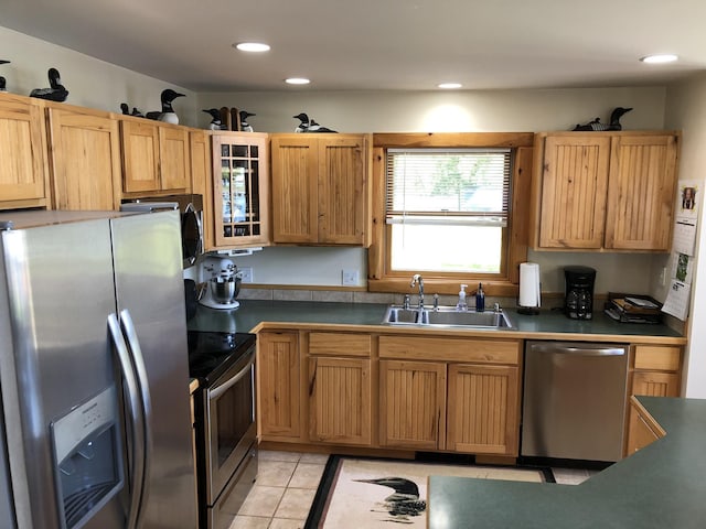 kitchen featuring glass insert cabinets, recessed lighting, appliances with stainless steel finishes, light tile patterned flooring, and a sink