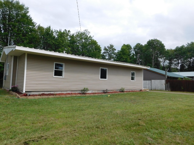 view of property exterior with a lawn and fence