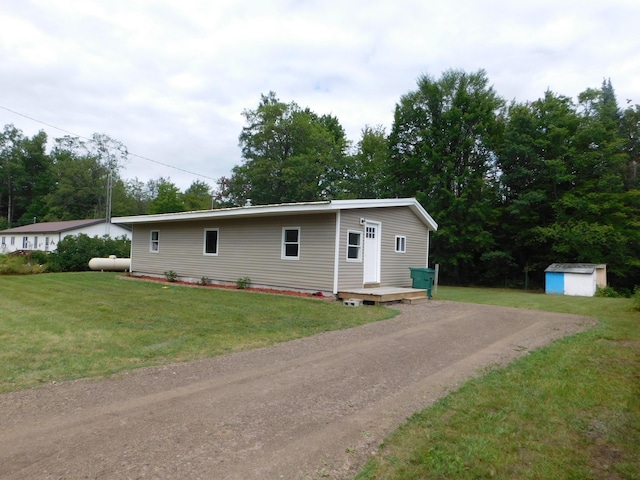 view of front of house with a front yard, an outdoor structure, a shed, and dirt driveway