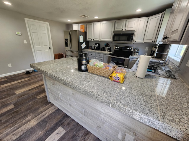 kitchen with tile countertops, recessed lighting, baseboards, and appliances with stainless steel finishes