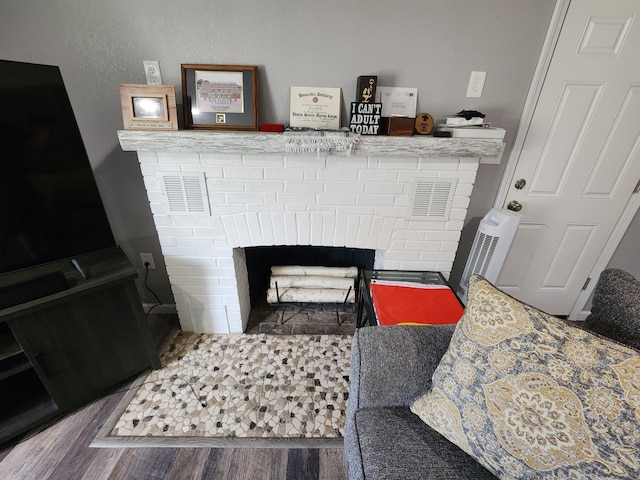 details featuring visible vents, a brick fireplace, and wood finished floors