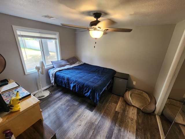 bedroom featuring visible vents, a textured ceiling, a ceiling fan, and wood finished floors