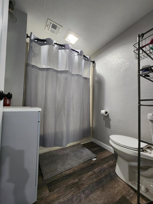 full bath featuring visible vents, toilet, wood finished floors, a shower with shower curtain, and baseboards