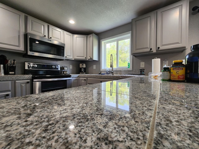 kitchen with recessed lighting, a sink, appliances with stainless steel finishes, a textured ceiling, and white cabinetry