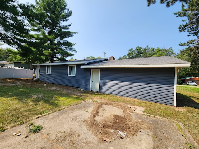 back of property featuring a yard, fence, and a chimney