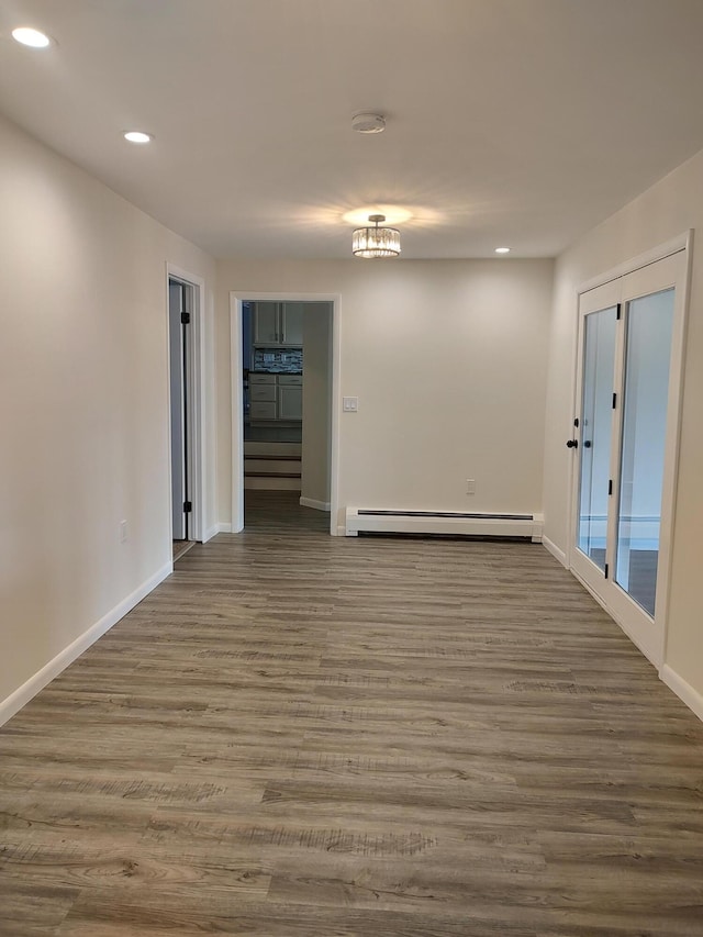 empty room with baseboard heating, recessed lighting, baseboards, and wood finished floors