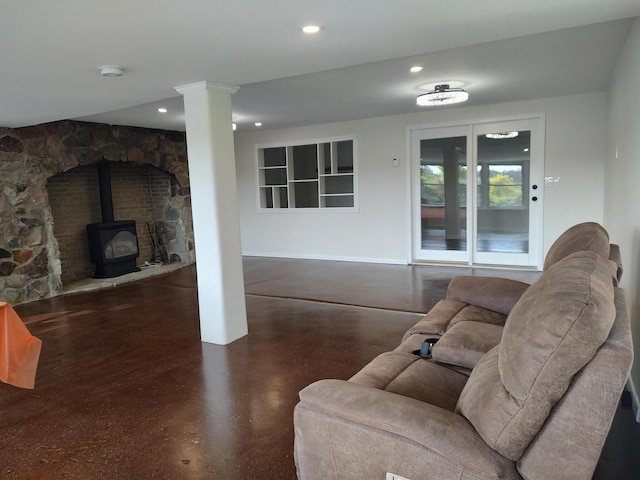 living room featuring recessed lighting, concrete flooring, ornate columns, and a wood stove