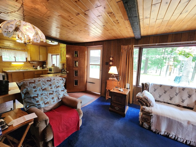 carpeted living area featuring wooden walls, wooden ceiling, and a sink