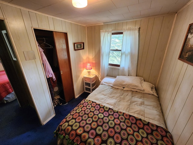 bedroom with dark colored carpet, a closet, and wooden walls