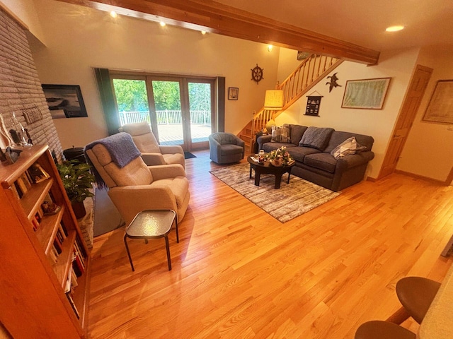 living room featuring stairway, beamed ceiling, and light wood-style floors