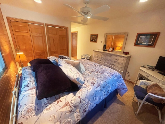 carpeted bedroom with multiple closets and a ceiling fan