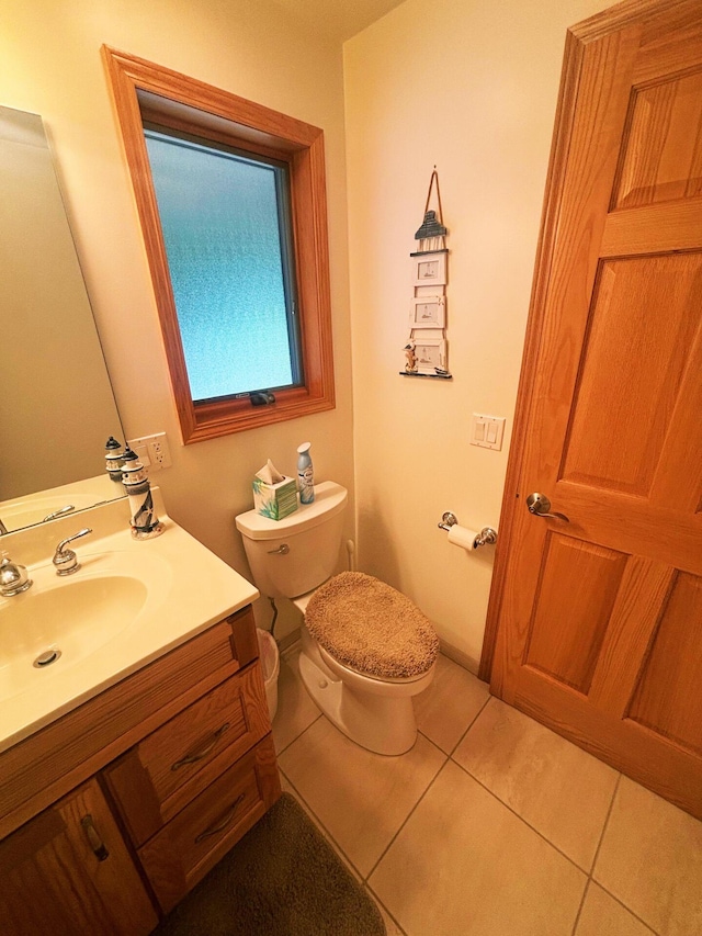 half bathroom featuring vanity, tile patterned floors, and toilet