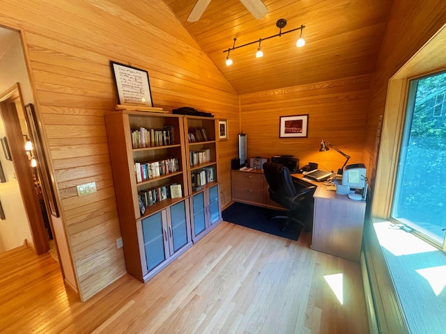 office area with light wood-type flooring, lofted ceiling, wooden walls, and track lighting