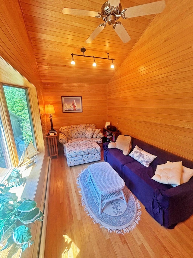 living room featuring wood finished floors, wooden walls, wooden ceiling, rail lighting, and lofted ceiling